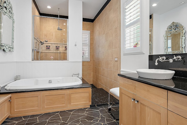 bathroom featuring a garden tub, wainscoting, vanity, and a tile shower