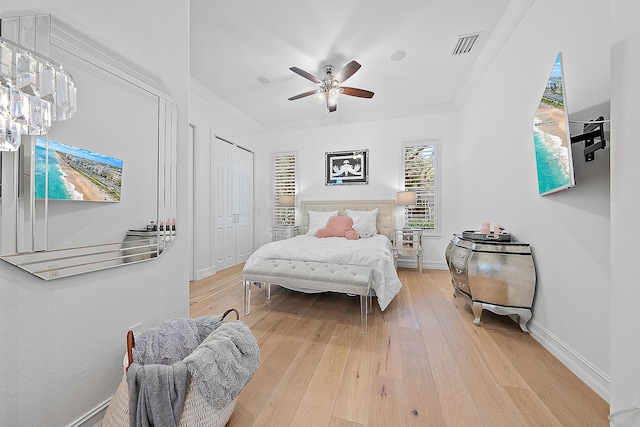 bedroom with visible vents, crown molding, baseboards, light wood-style floors, and a ceiling fan