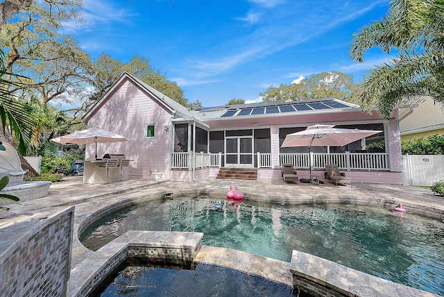 back of property featuring a patio, a pool with connected hot tub, and a sunroom