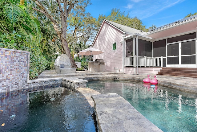 outdoor pool featuring an outdoor kitchen, a patio, and a sunroom