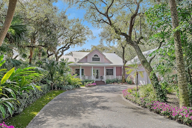 view of front of property with covered porch, driveway, and metal roof