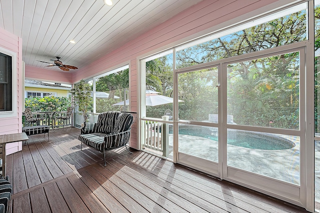 unfurnished sunroom featuring wood ceiling and a ceiling fan