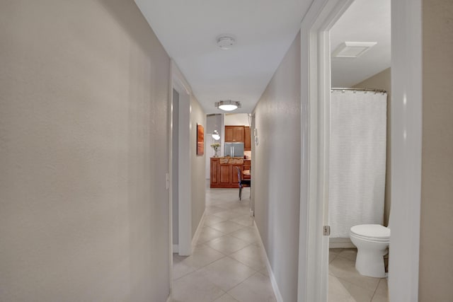 hall featuring light tile patterned flooring and baseboards