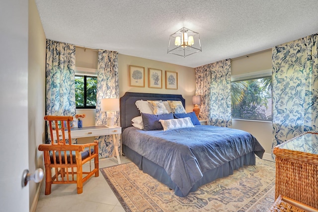 bedroom with a textured ceiling, baseboards, and an inviting chandelier