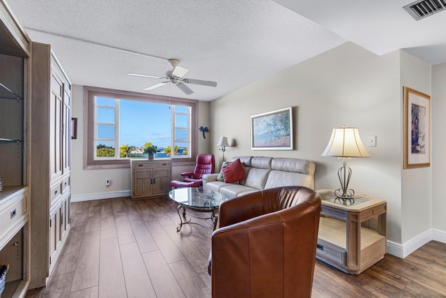 living room featuring ceiling fan, dark hardwood / wood-style flooring, and a textured ceiling