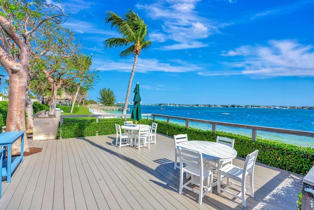 wooden terrace featuring outdoor dining area and a water view