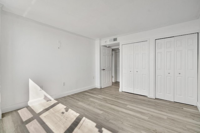 5600 N Flagler Dr Unit 1605, West Palm Beach, FL 33407 - unfurnished bedroom featuring crown molding, two closets, visible vents, light wood-style flooring, and baseboards