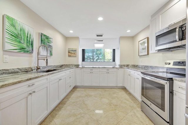 5600 N Flagler Dr Unit 1605, West Palm Beach, FL 33407 - kitchen featuring appliances with stainless steel finishes, white cabinetry, a sink, and light stone counters