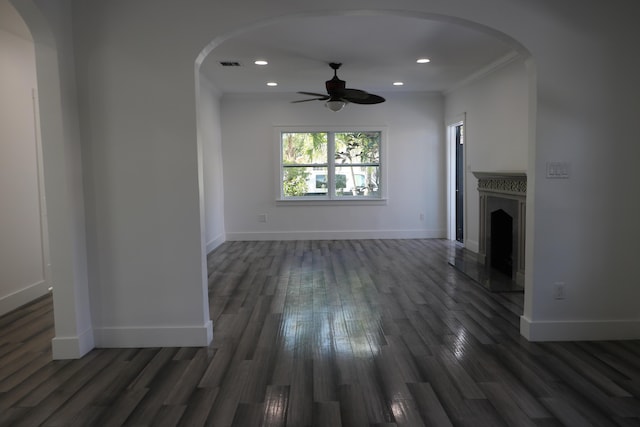 unfurnished living room featuring dark wood-type flooring, arched walkways, visible vents, and baseboards