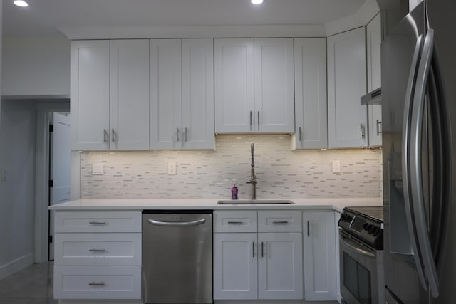 kitchen with stainless steel appliances, light countertops, a sink, and white cabinetry