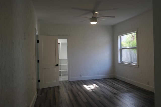 spare room with baseboards, dark wood finished floors, and a ceiling fan