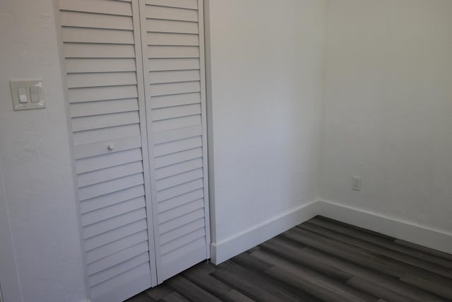 empty room with dark wood-style flooring and baseboards