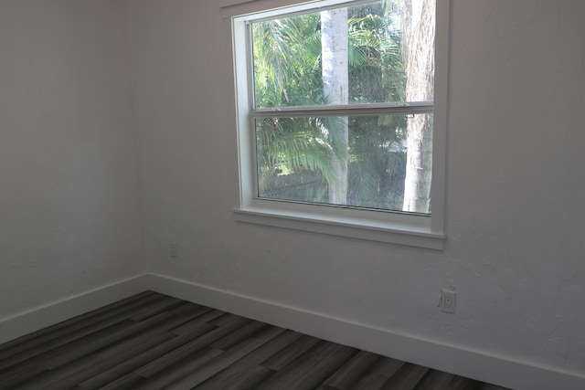 unfurnished room featuring dark wood-style flooring and baseboards