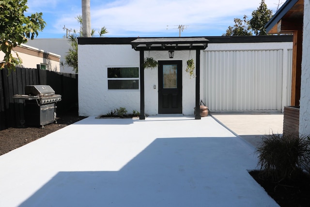 exterior space with stucco siding, fence, and a patio