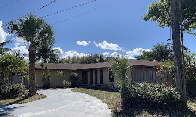 view of front of house featuring driveway, fence, and stucco siding