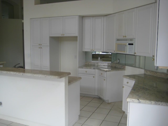 kitchen with white cabinetry, light stone countertops, and light tile patterned floors