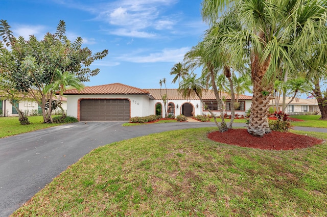 mediterranean / spanish-style house featuring an attached garage, driveway, a front lawn, and stucco siding