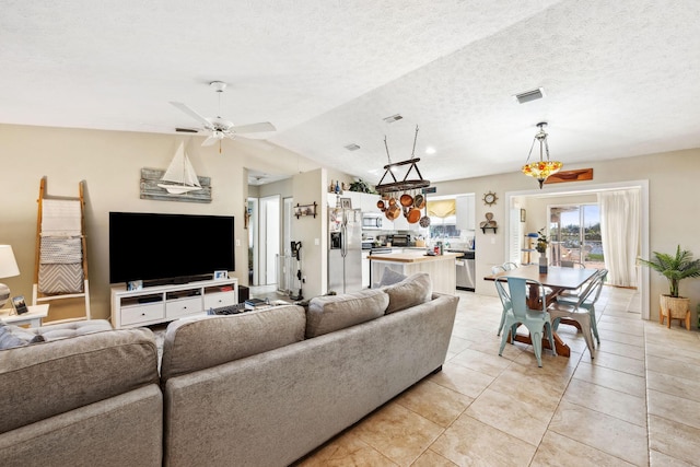 living room featuring vaulted ceiling, ceiling fan, light tile patterned floors, and a textured ceiling