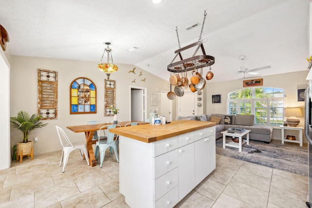 kitchen featuring hanging light fixtures, butcher block counters, white cabinets, lofted ceiling, and a center island