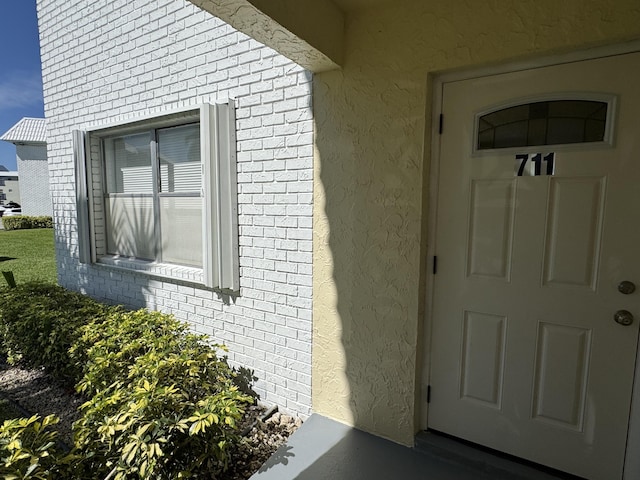 property entrance featuring brick siding and stucco siding