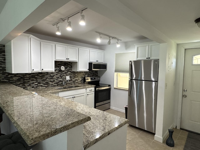 kitchen featuring decorative backsplash, a peninsula, stainless steel appliances, white cabinetry, and a sink