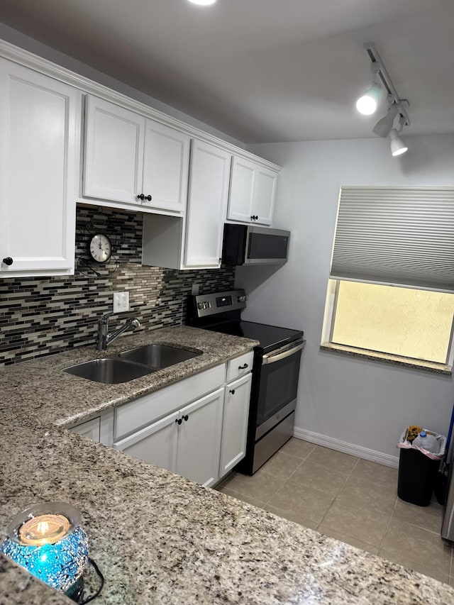 kitchen with white cabinets, decorative backsplash, appliances with stainless steel finishes, a sink, and light tile patterned flooring