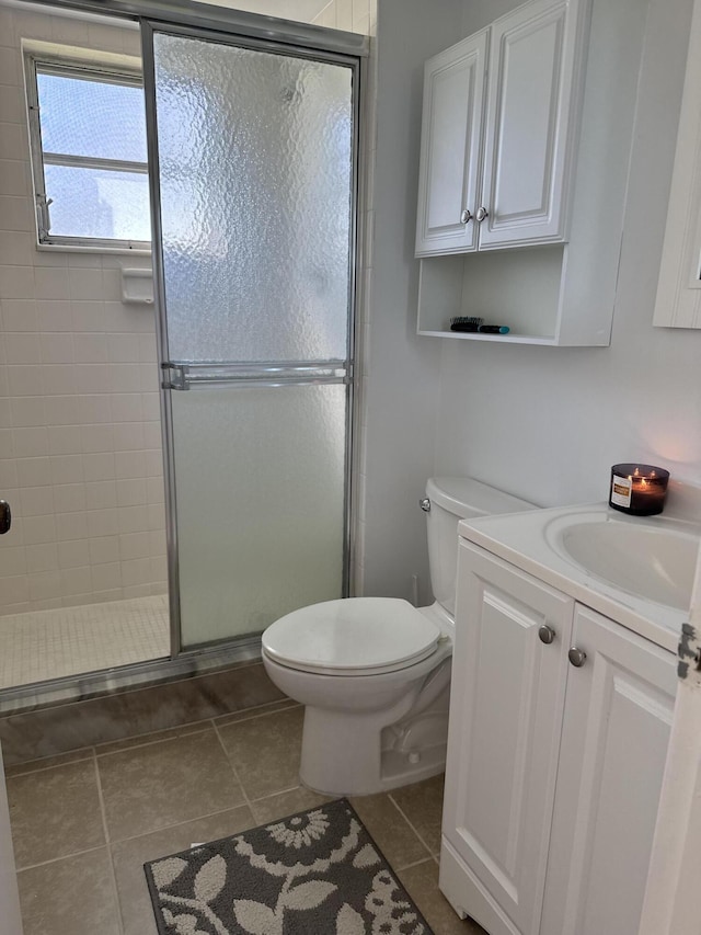 bathroom with toilet, a stall shower, vanity, and tile patterned floors