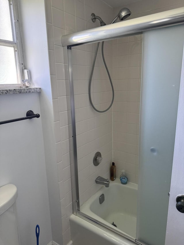 full bathroom featuring toilet and shower / bath combination with glass door