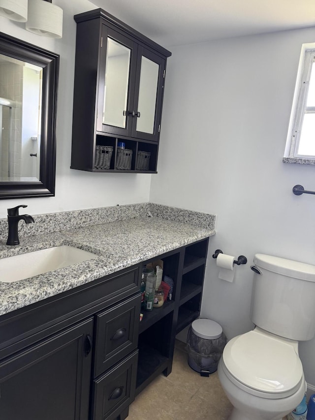 bathroom featuring a shower with shower door, vanity, toilet, and tile patterned floors