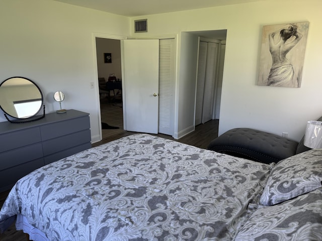 bedroom with a closet, wood finished floors, visible vents, and baseboards