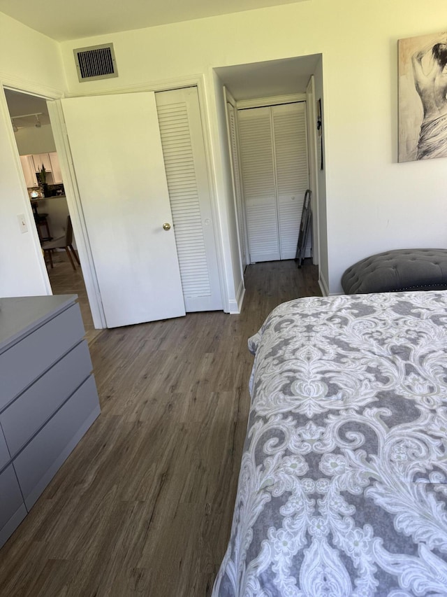 bedroom with dark wood-type flooring, a closet, and visible vents