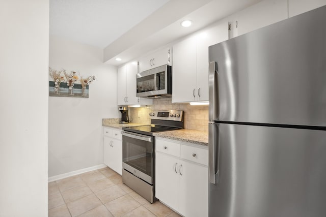 kitchen featuring appliances with stainless steel finishes, tasteful backsplash, light stone counters, light tile patterned floors, and white cabinetry