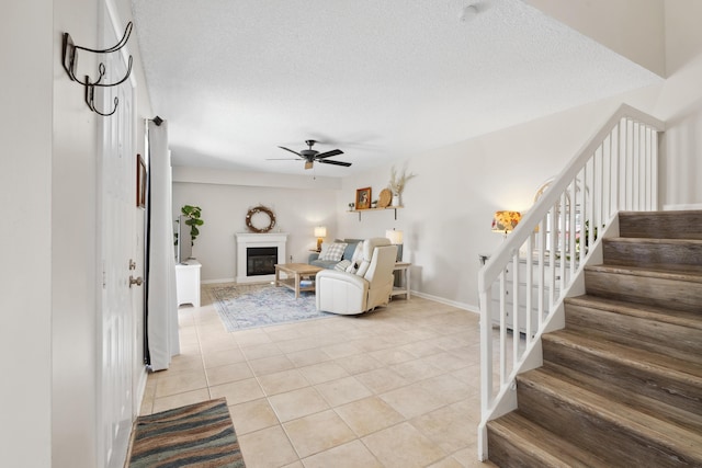 living room featuring a textured ceiling, ceiling fan, and light tile patterned floors