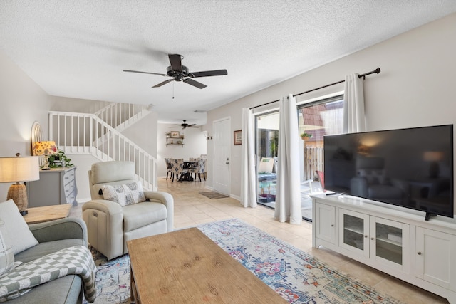 living room with ceiling fan, light tile patterned flooring, and a textured ceiling