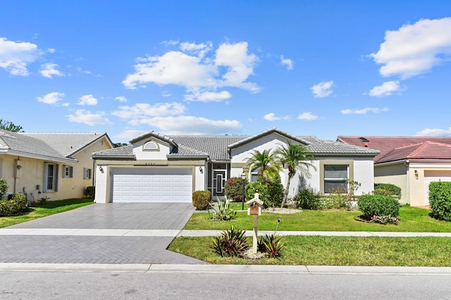 view of front facade featuring stucco siding, a front lawn, a tile roof, decorative driveway, and a garage