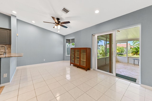 empty room featuring a ceiling fan, light tile patterned floors, a healthy amount of sunlight, and visible vents