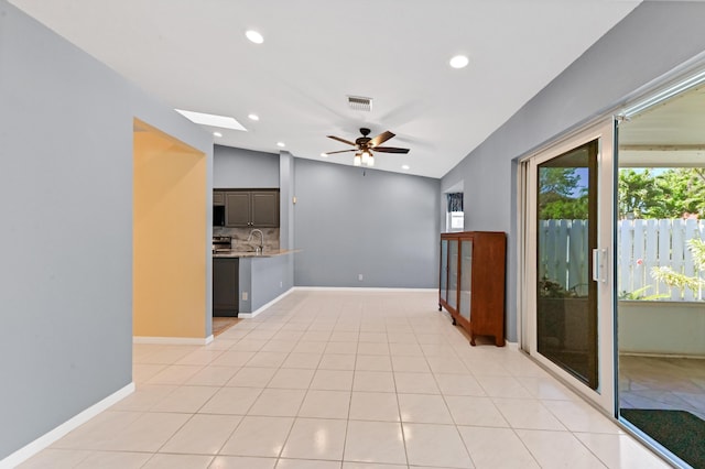 unfurnished room featuring baseboards, visible vents, light tile patterned flooring, ceiling fan, and a sink