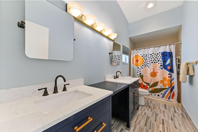 full bath featuring a sink, toilet, two vanities, and wood finished floors