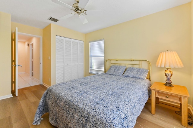 bedroom featuring visible vents, baseboards, ceiling fan, wood finished floors, and a closet