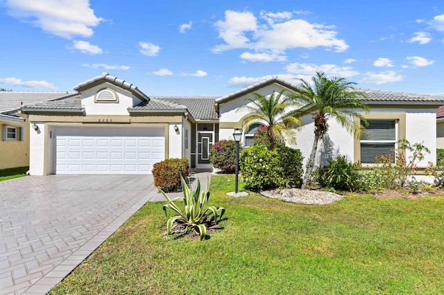 ranch-style home featuring stucco siding, a tile roof, decorative driveway, and a garage