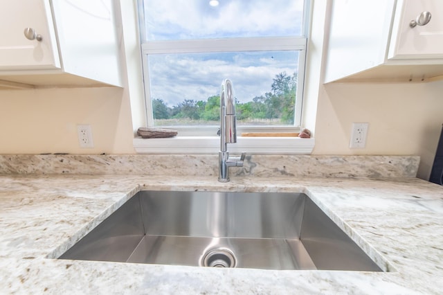 details featuring white cabinetry, sink, and light stone countertops