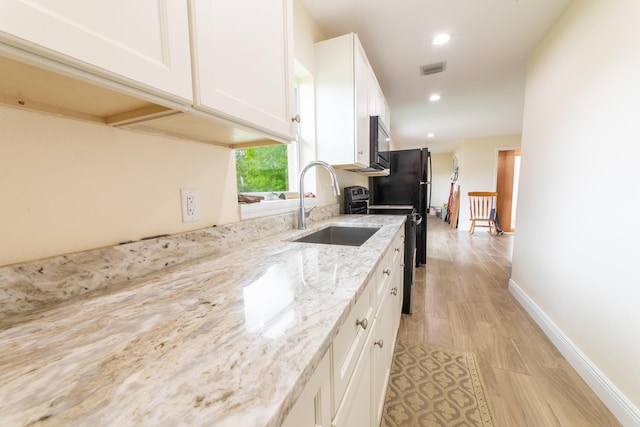 kitchen featuring white cabinetry, stove, light hardwood / wood-style flooring, light stone countertops, and sink