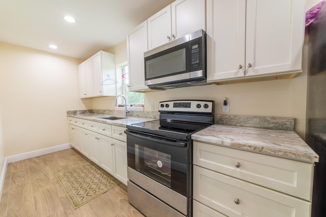 kitchen featuring sink, white cabinets, stainless steel appliances, and light stone counters