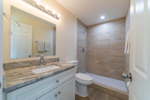 bathroom with tiled shower, vanity, and toilet