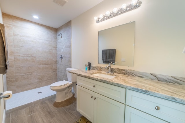 bathroom with vanity, tiled shower, and toilet