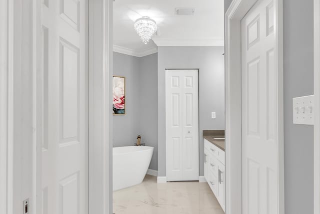 bathroom featuring marble finish floor, crown molding, a closet, vanity, and a freestanding tub