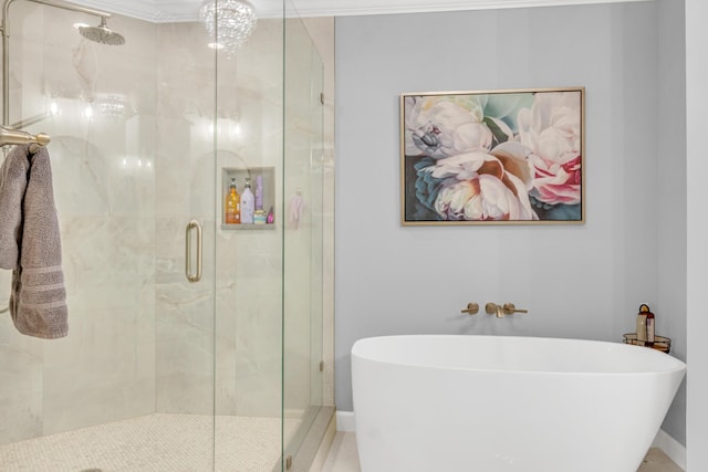 full bathroom with ornamental molding, a freestanding bath, a shower stall, and baseboards