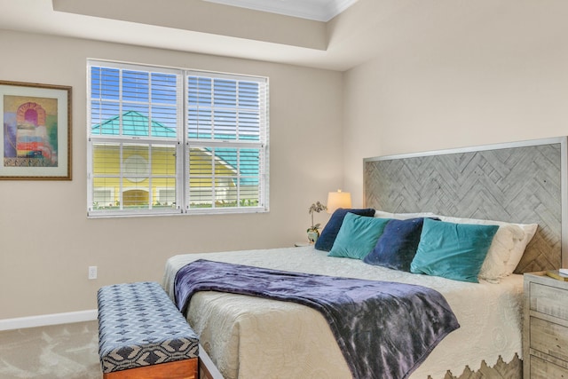 carpeted bedroom featuring a raised ceiling, crown molding, and baseboards