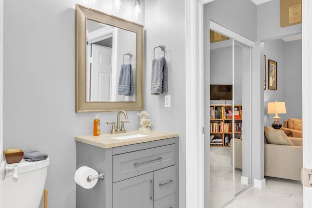 half bath with marble finish floor, vanity, and toilet