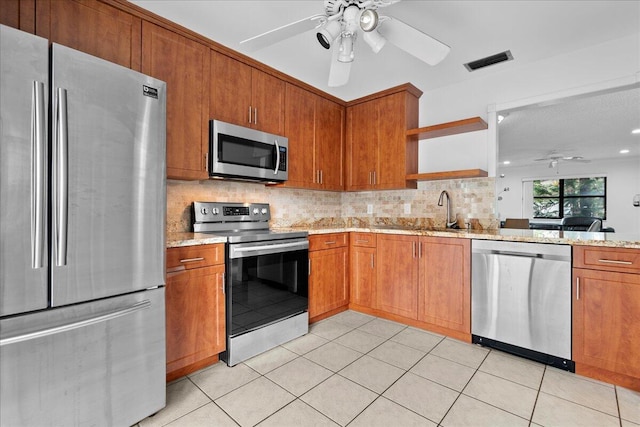 kitchen with light tile patterned floors, stainless steel appliances, backsplash, and light stone countertops